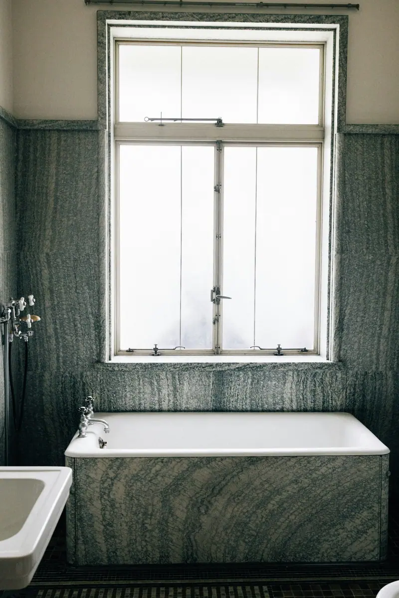 Baignoire de marbre vert sous une haute fenêtre