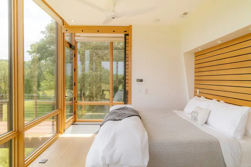 Chambre avec tête de lit en bois et fenêtre d’angle